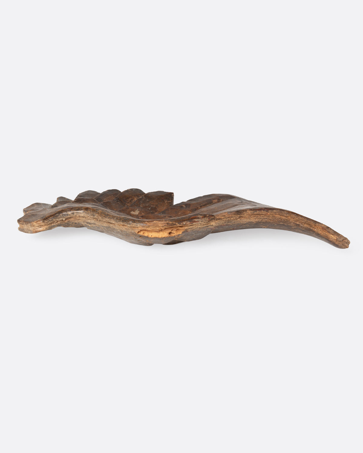 A wooden hand carved wing, shown from the side.