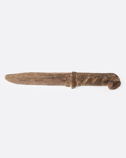 A hand carved wooden knife, shown from the side.