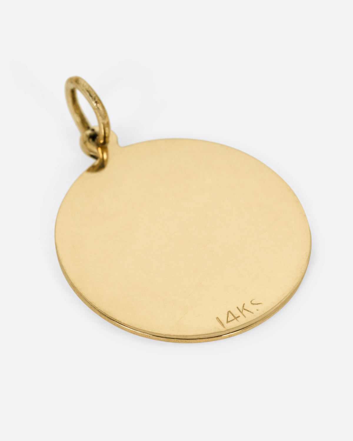 A round gold pendant with a sunburst radiating from a central engraved letter 'H', shown from the back.