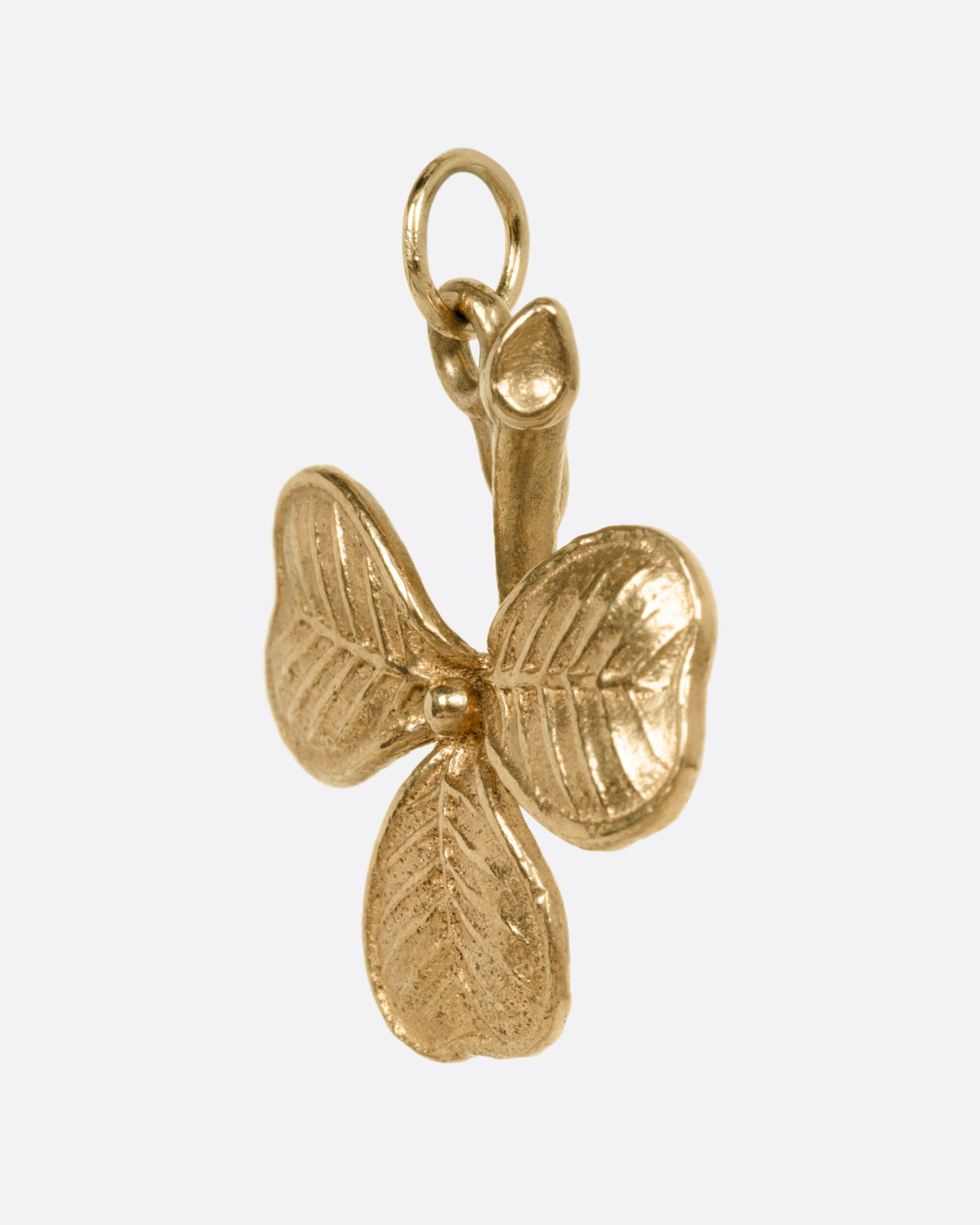 A yellow gold shamrock charm, shown from the side.