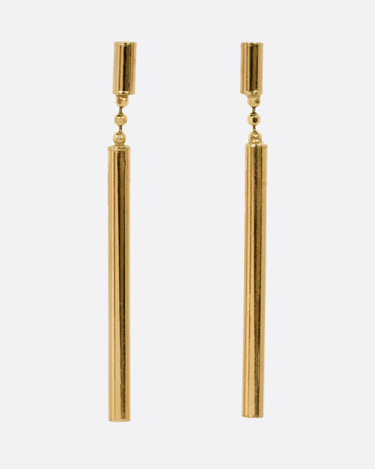 A pair of yellow gold drop earrings with a small cylindrical stud and a long, slender cylindrical dangle, shown from the front.
