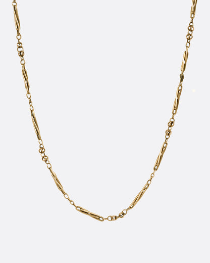 A yellow gold watch chain necklace with long twisted links, shown from the front.