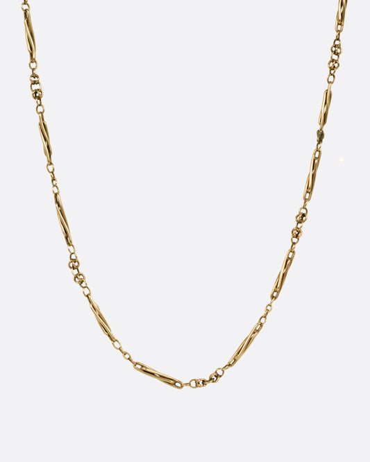 A yellow gold watch chain necklace with long twisted links, shown from the front.