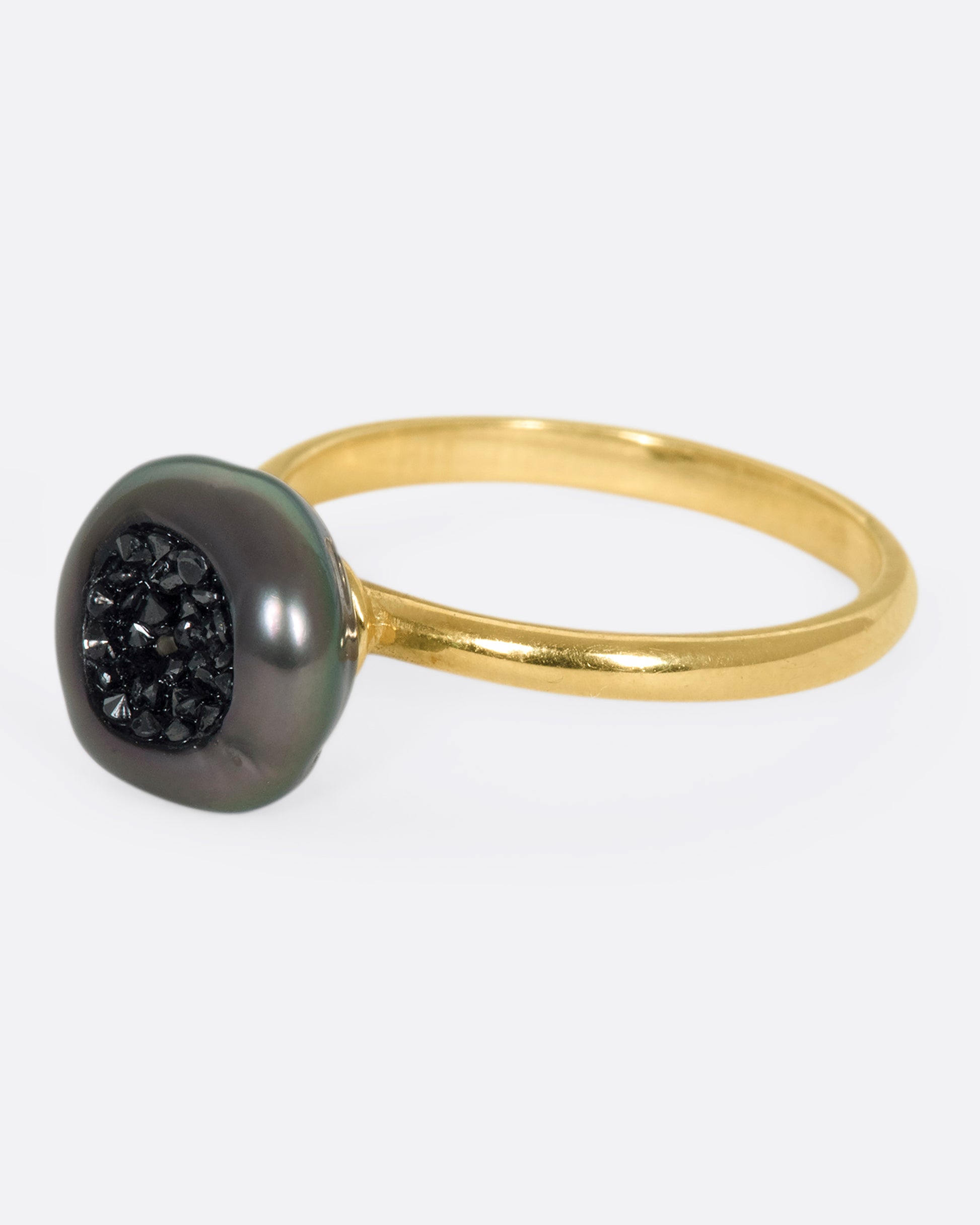 A 14k gold band with a carved Tahitian keshi pearl lined with black diamonds