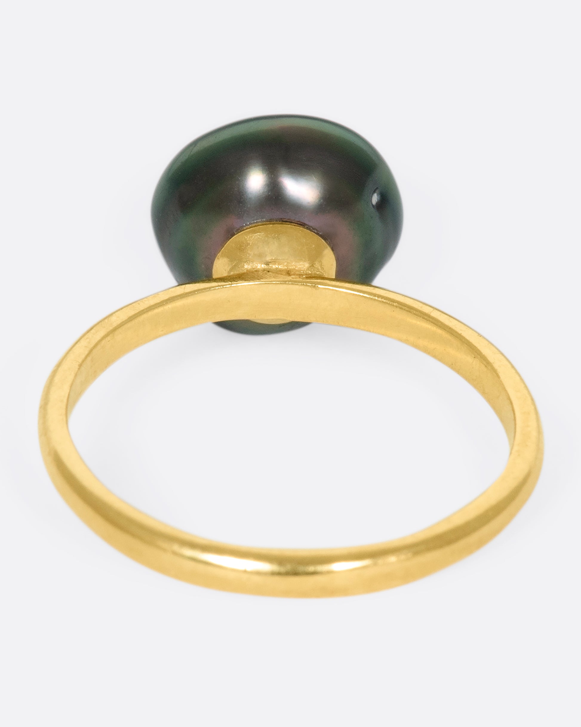 A 14k gold band with a carved Tahitian keshi pearl lined with black diamonds