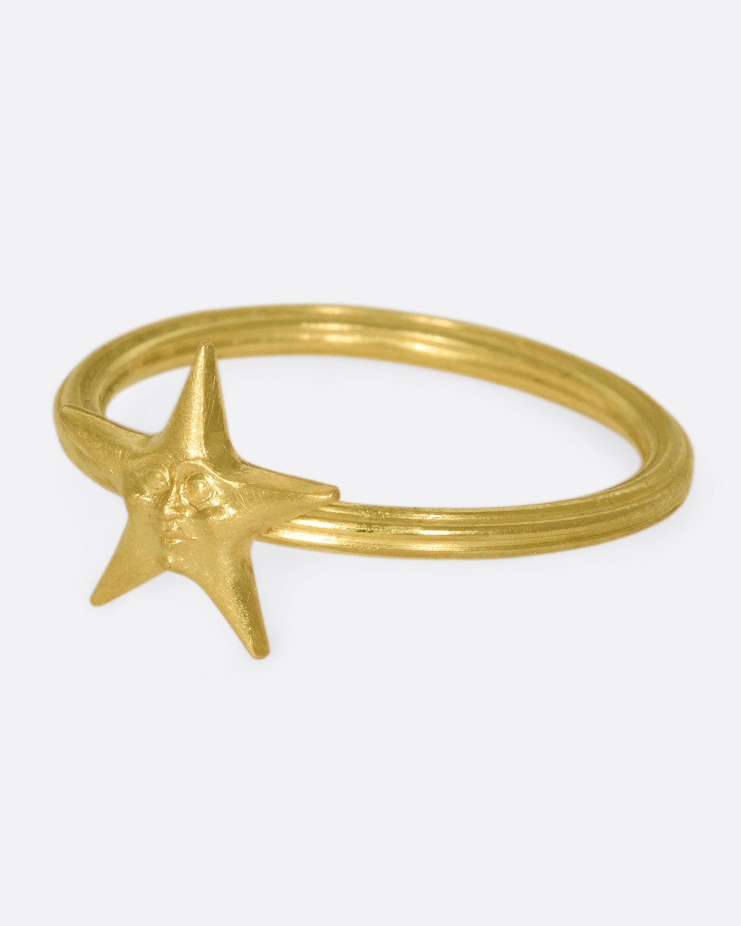 An 18k gold star ring with a sweet face emerging in the center.