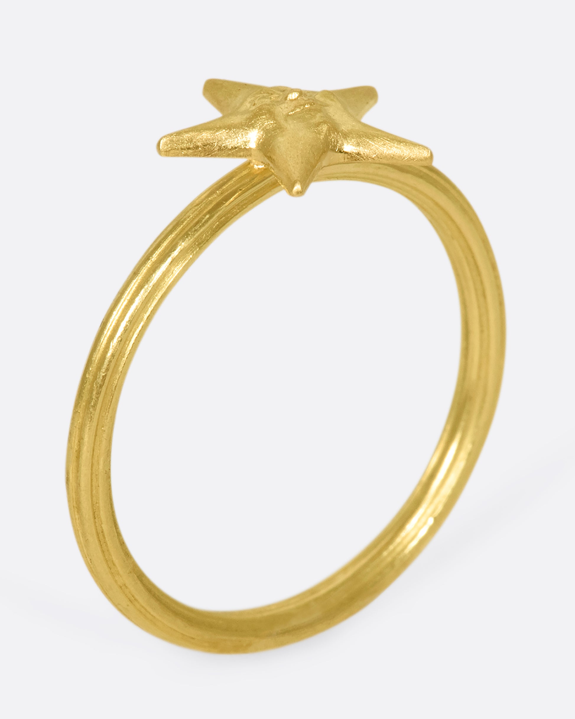 An 18k gold star ring with a sweet face emerging in the center.