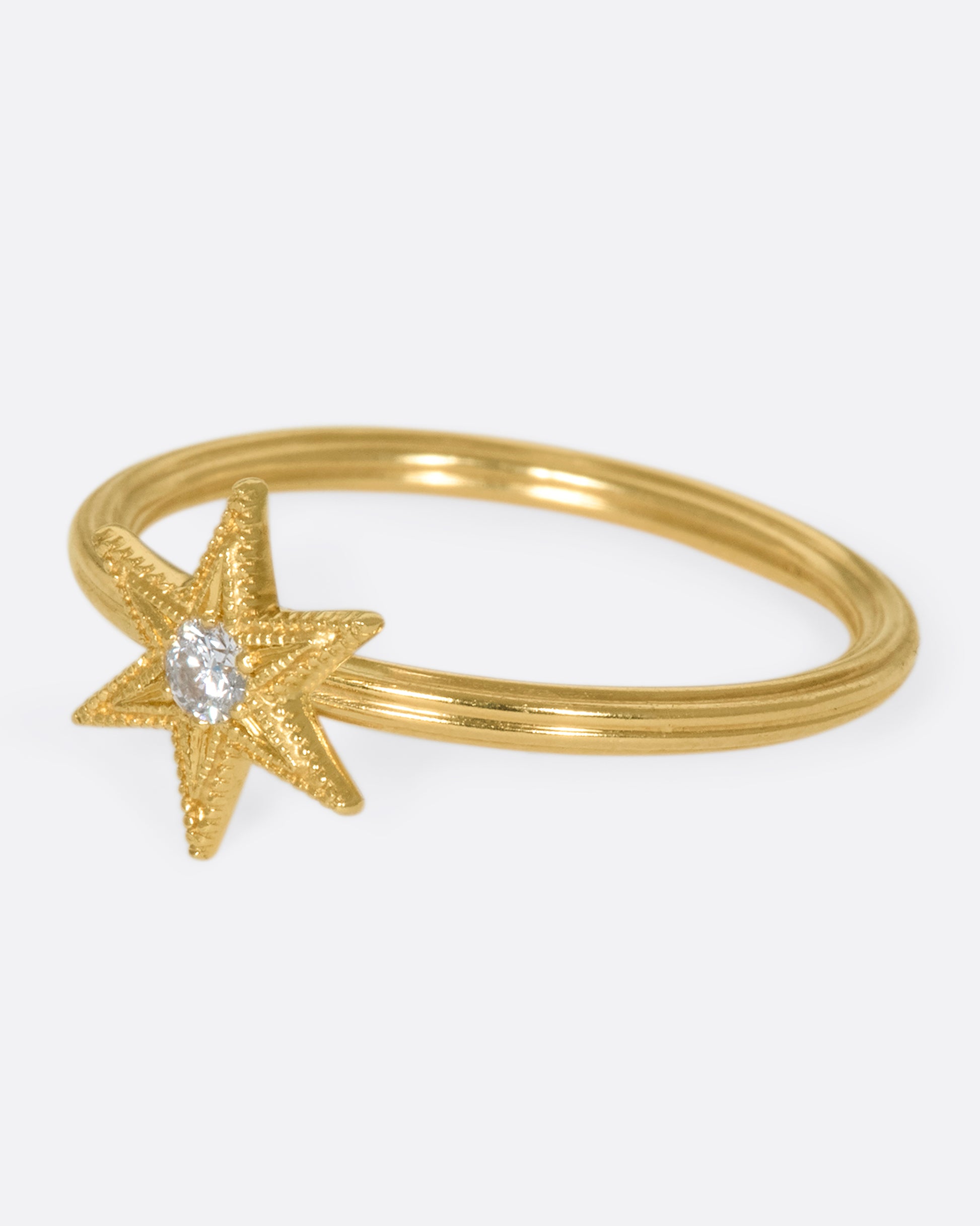 An 18k gold six-point star ring with a round diamond nestled in the center