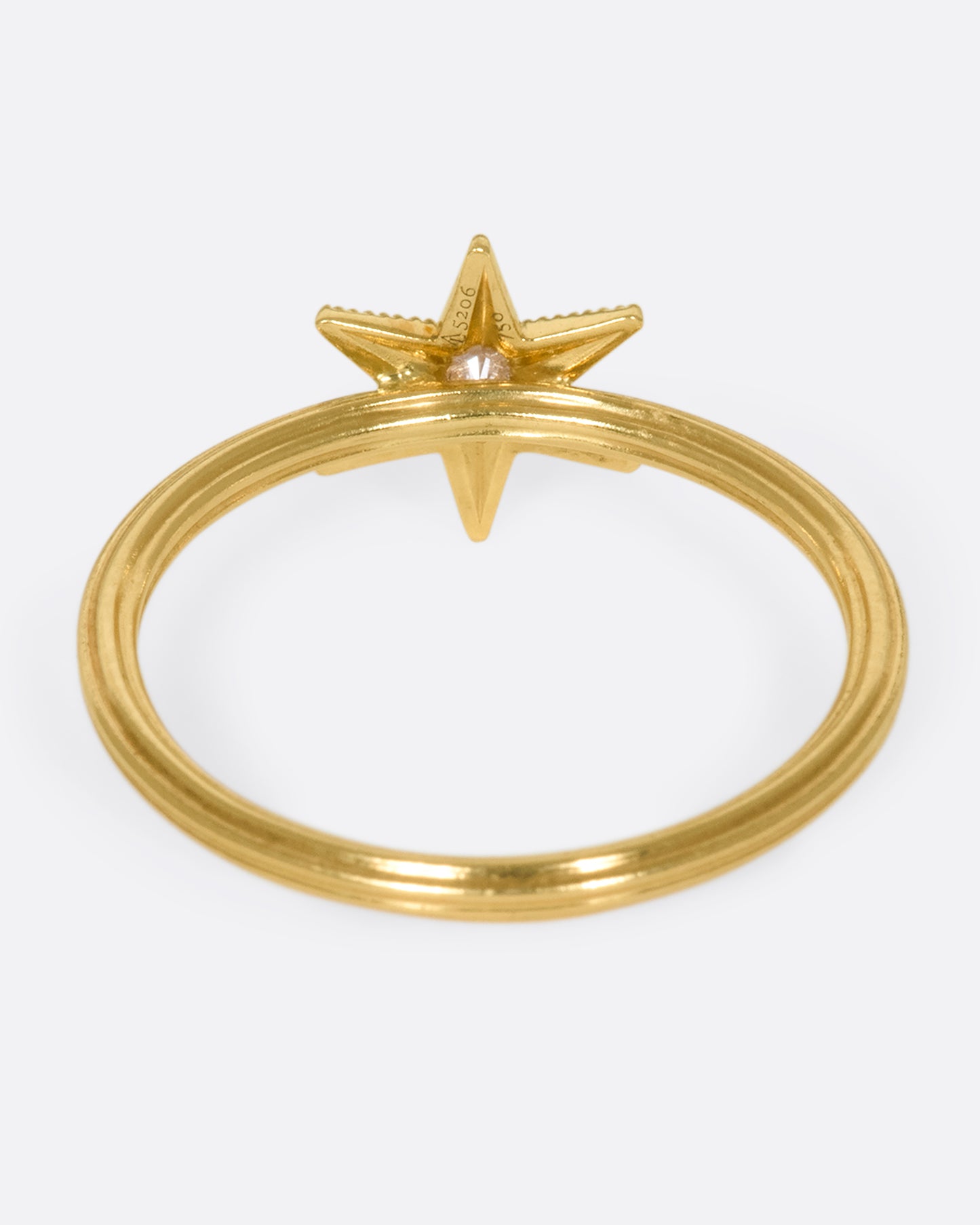 An 18k gold six-point star ring with a round diamond nestled in the center