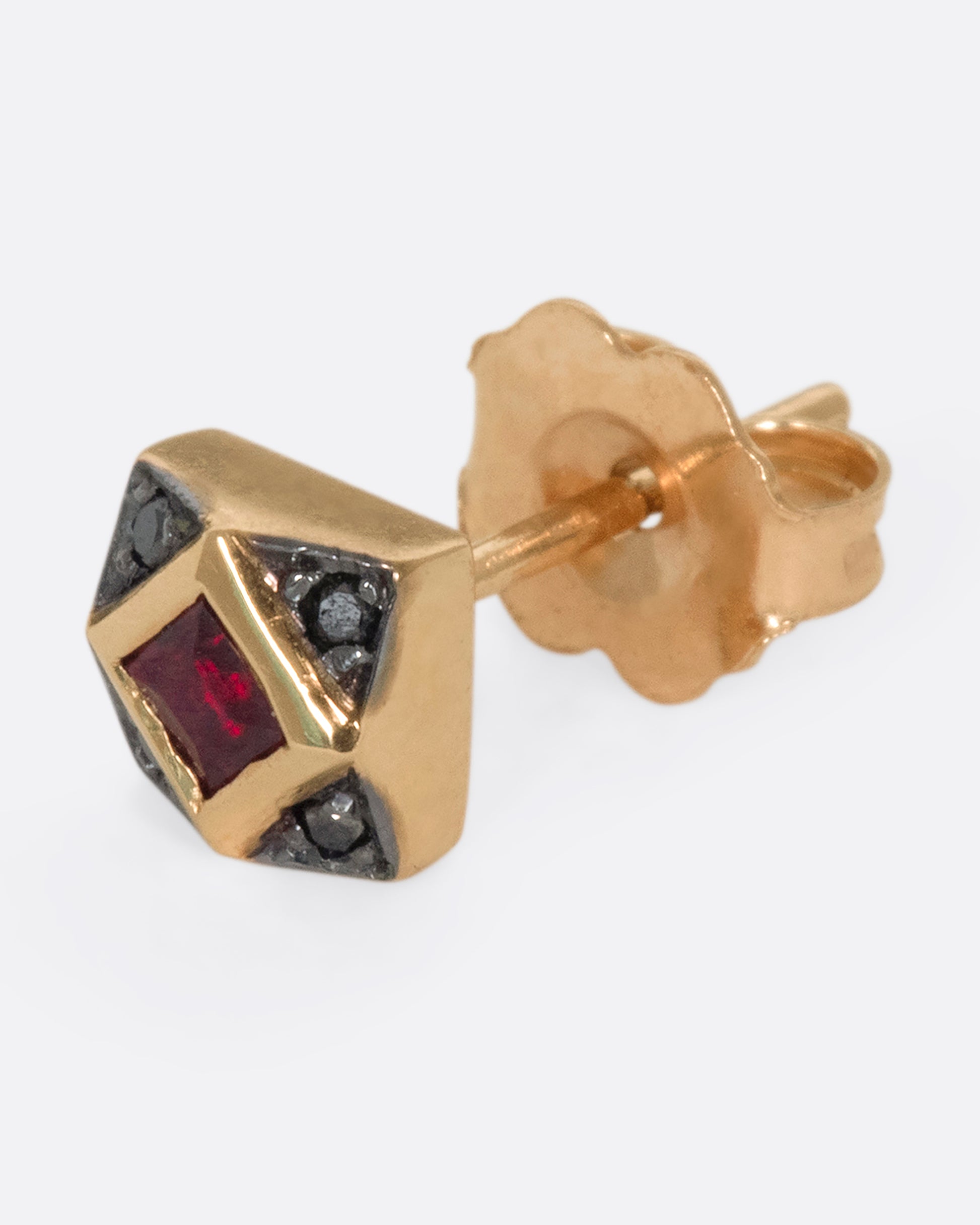 A 14k rose gold diamond stud featuring a princess cut ruby surrounded by four black diamonds