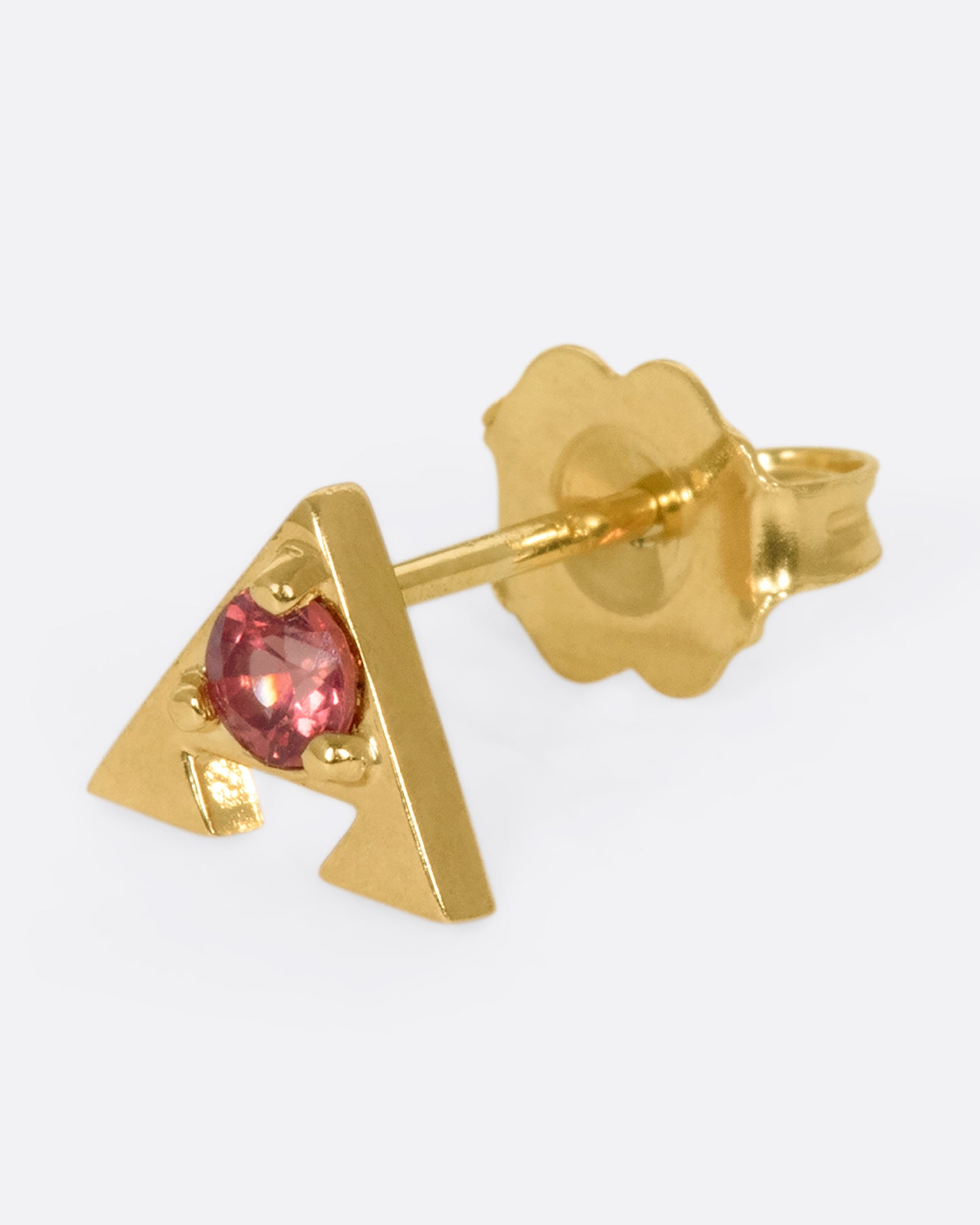 A 14k gold amulet stud with an orange sapphire in the center