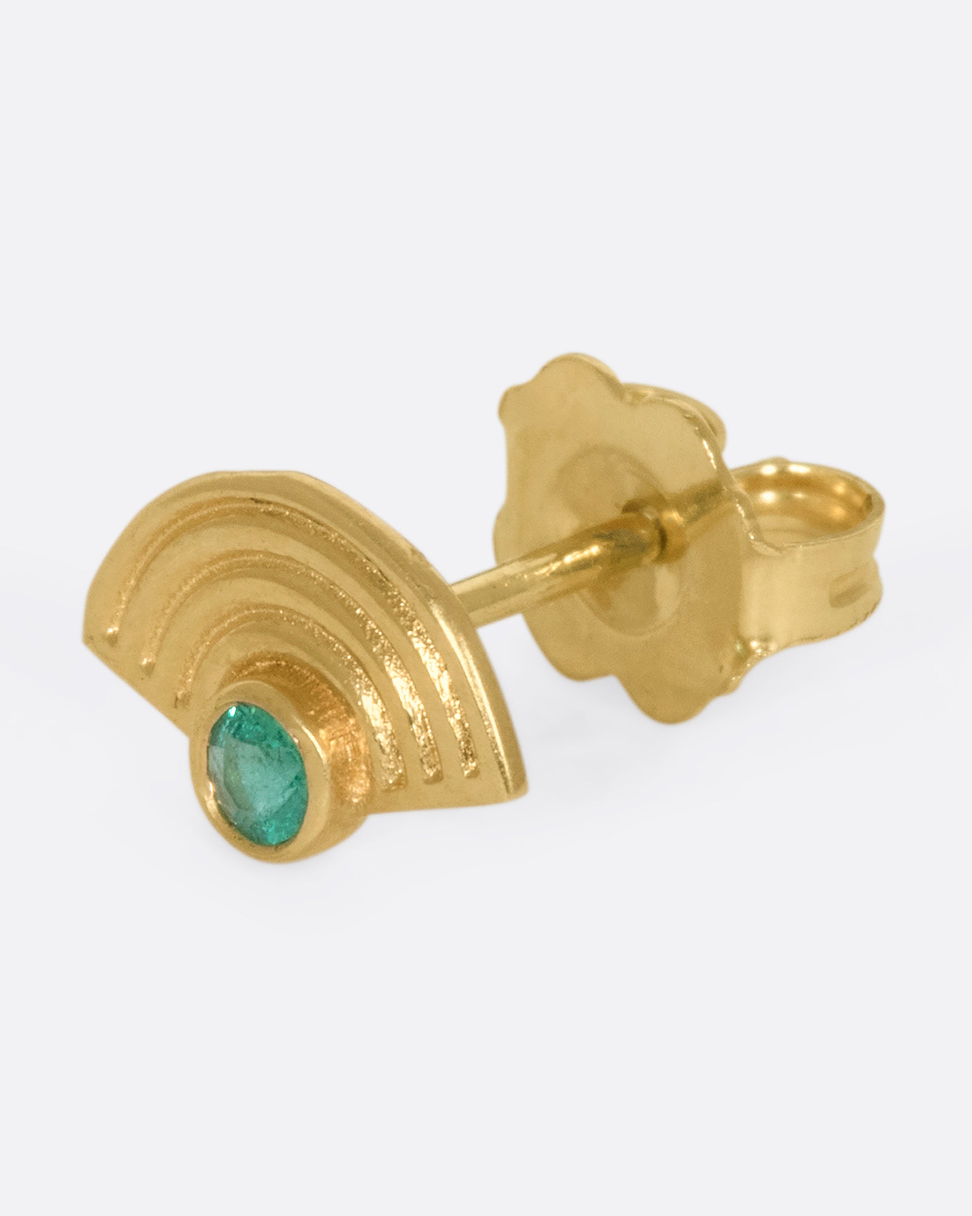 A 14k gold semi-circular spiral stud with an emerald glowing in the center