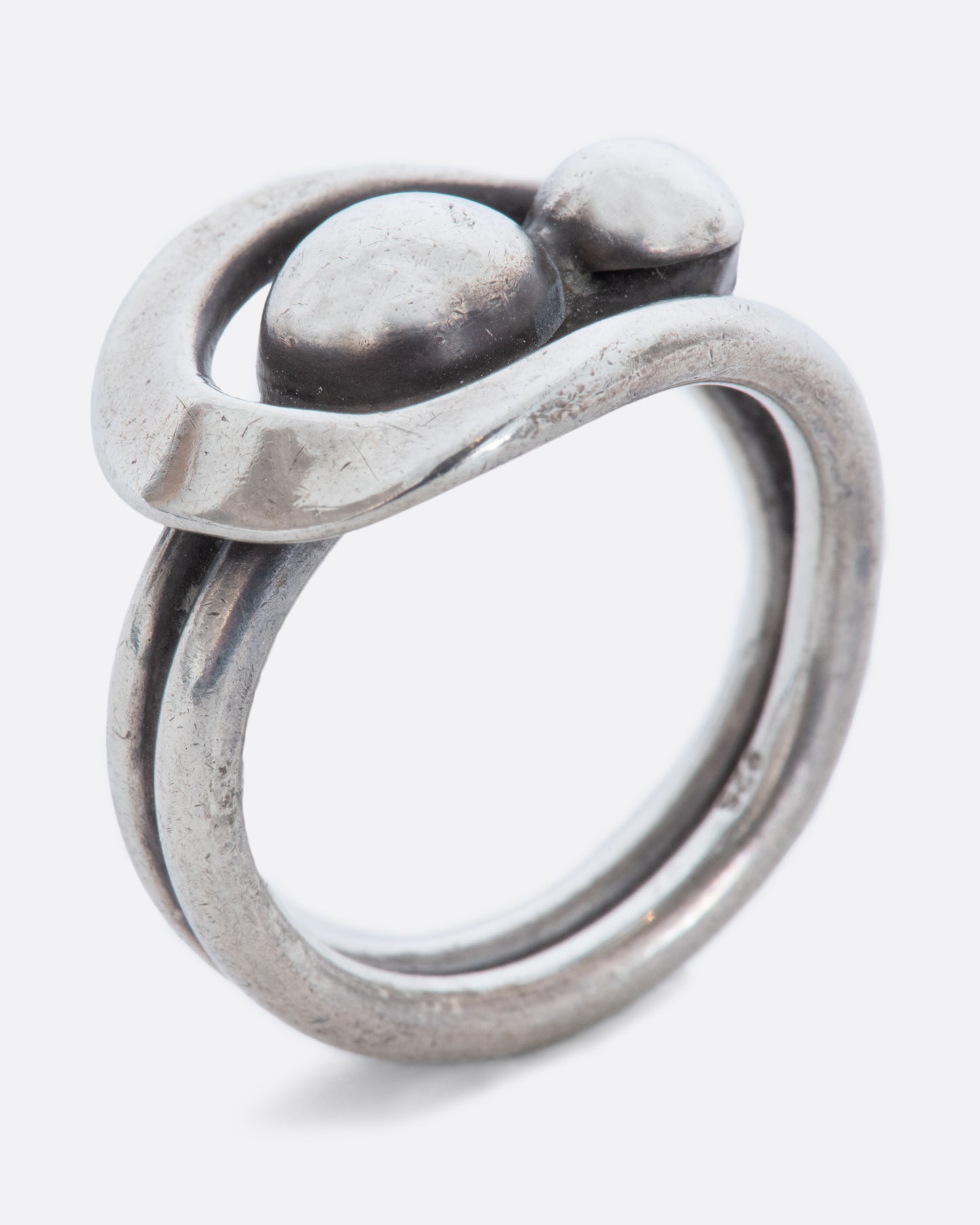 A sterling silver wrap ring with two spheres at the center. Shown standing from the side.