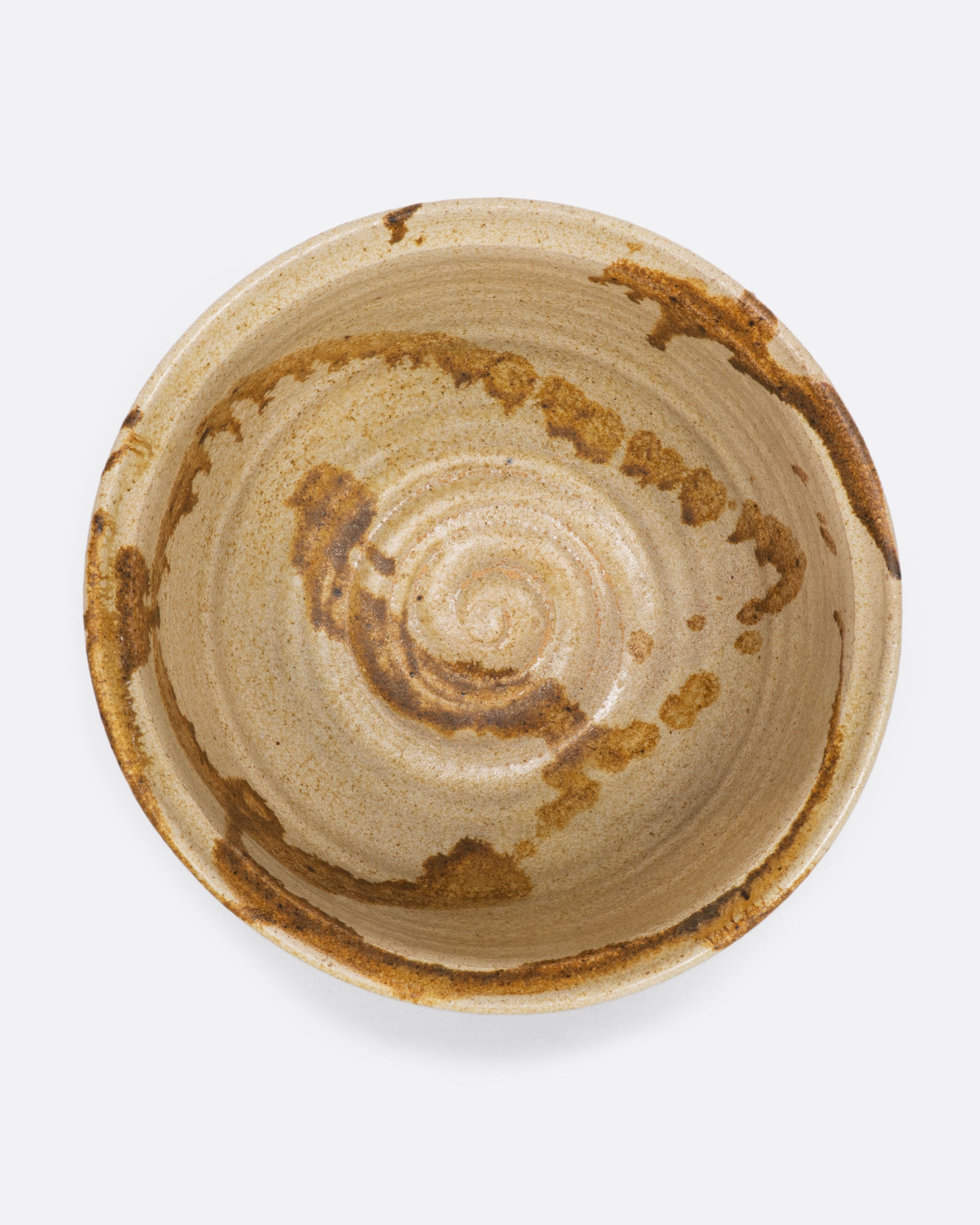 A beige ceramic bowl with brown splatter. View of interior.