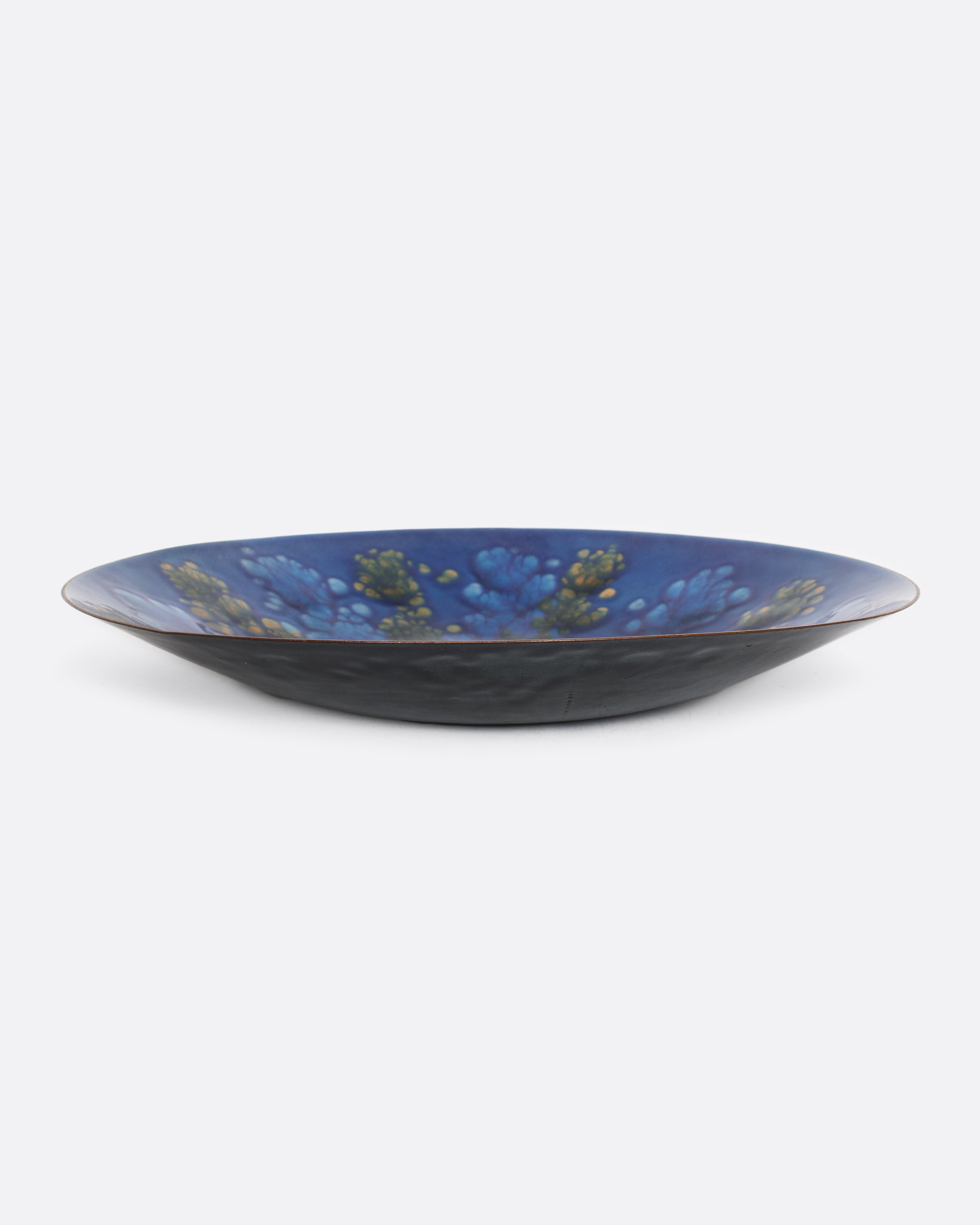 Blue and gold enameled plate. Sitting on flat surface.