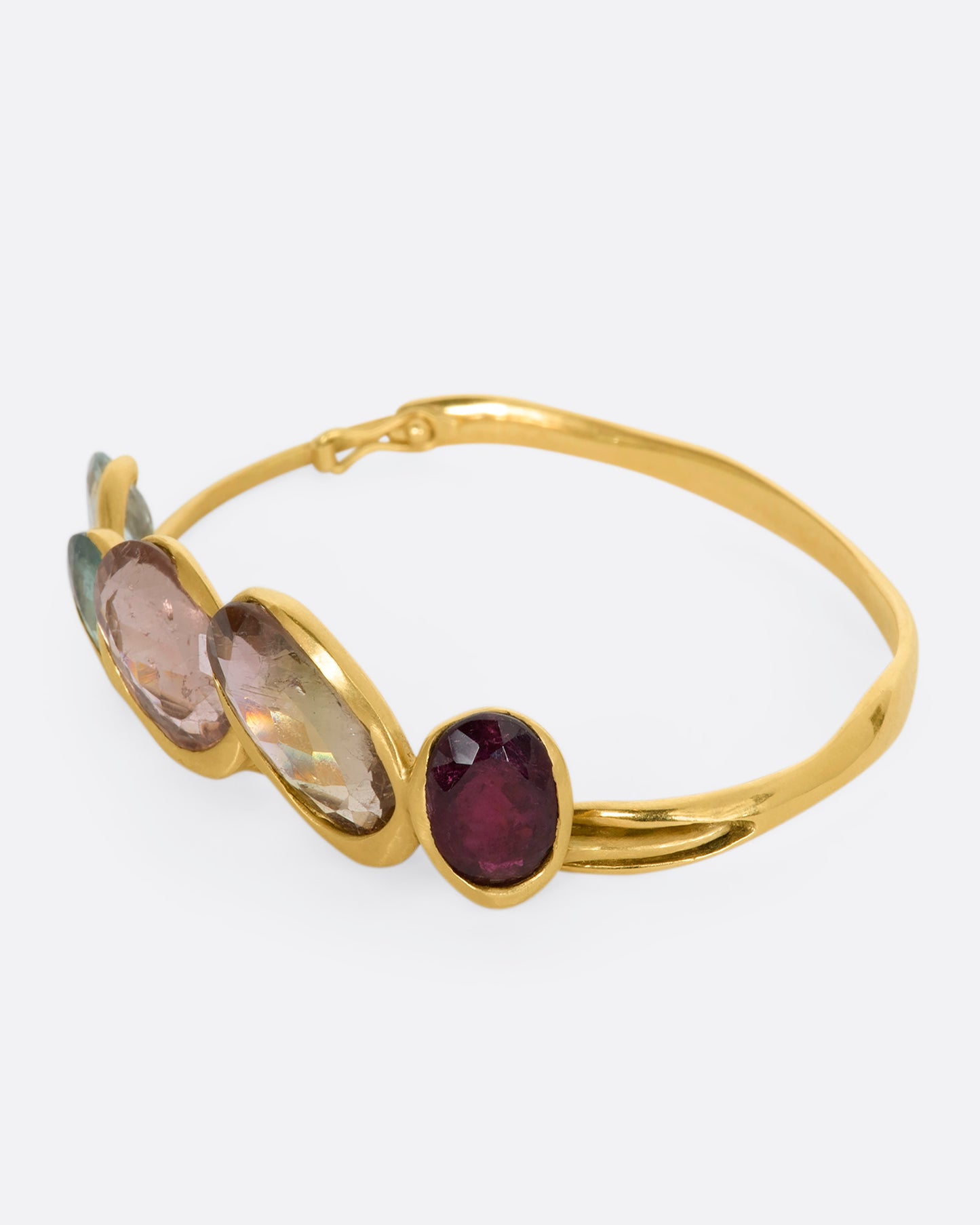 A yellow gold hinged bracelet crowned with five large different color tourmalines. View from the alternate side.
