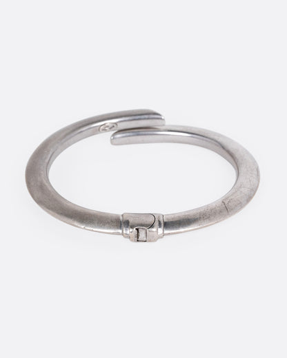 A silver wrap bracelet with hinged back, shown from the back.