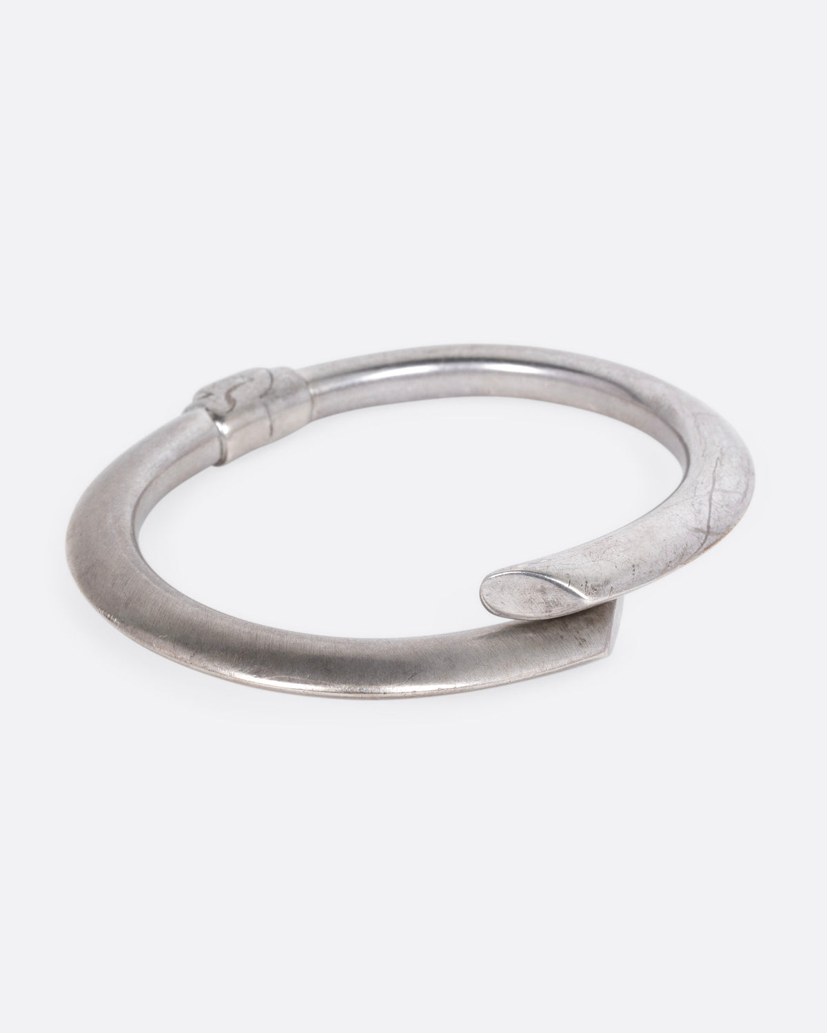 A silver wrap bracelet with hinged back, shown from the side.