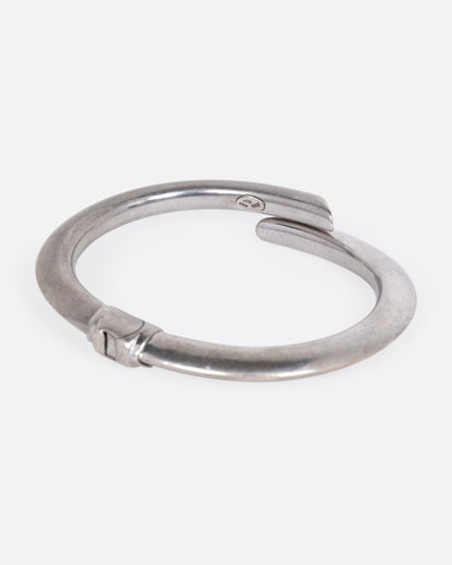 A silver wrap bracelet with hinged back, shown from the side.