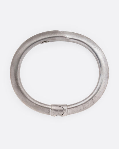 A silver wrap bracelet with hinged back, shown from the top.