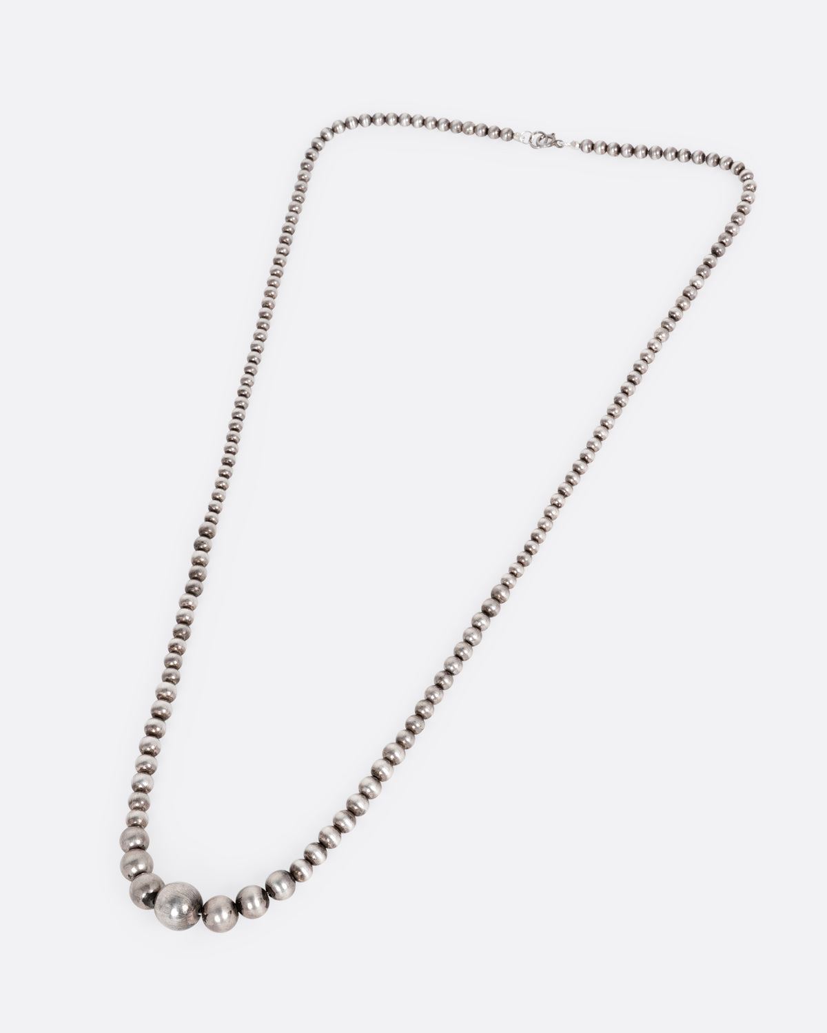 Vintage silver graduated bead necklace laid flat, showing the full length