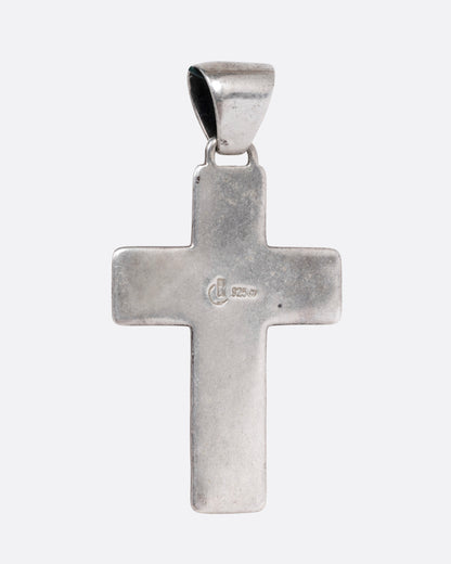 A silver cross with colorful inlay, shown from the back.