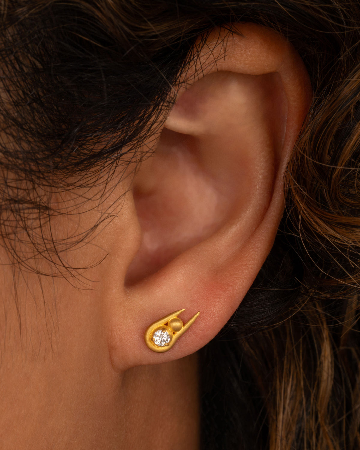Lori Leven stacked sphere earring in matte yellow gold worn on an ear, a round diamond above a gold ball in a long open frame