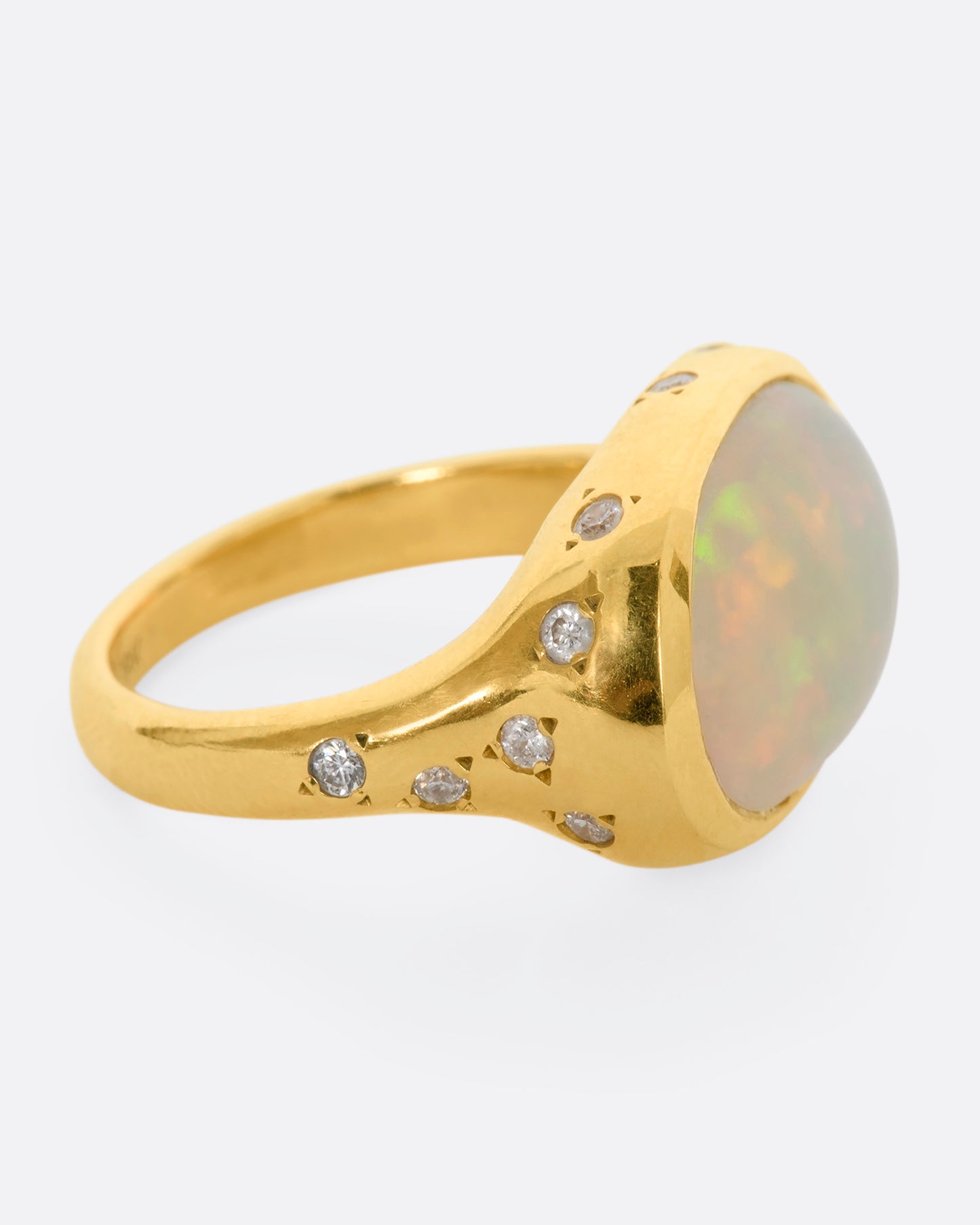 A polished yellow gold ring with a large east west oval Australian opal and diamonds on the setting and shoulders. View from the alternate side.