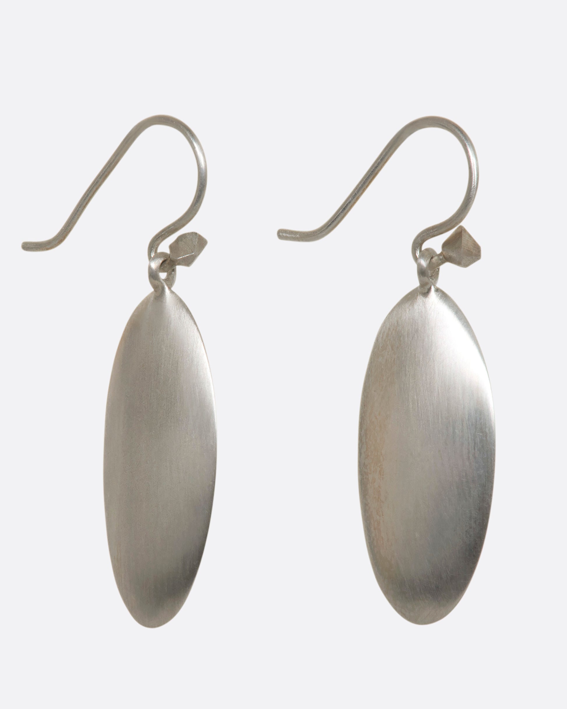 Sterling silver long flat oval dangle earrings. View from the side.