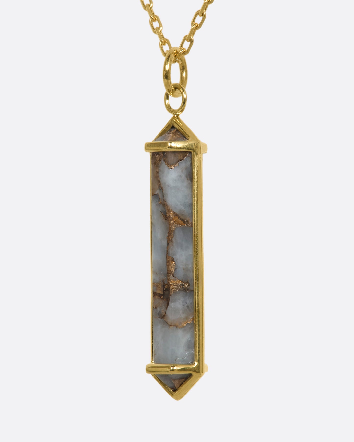 A yellow gold necklace with a geometric pink opal pendant. View from the side.