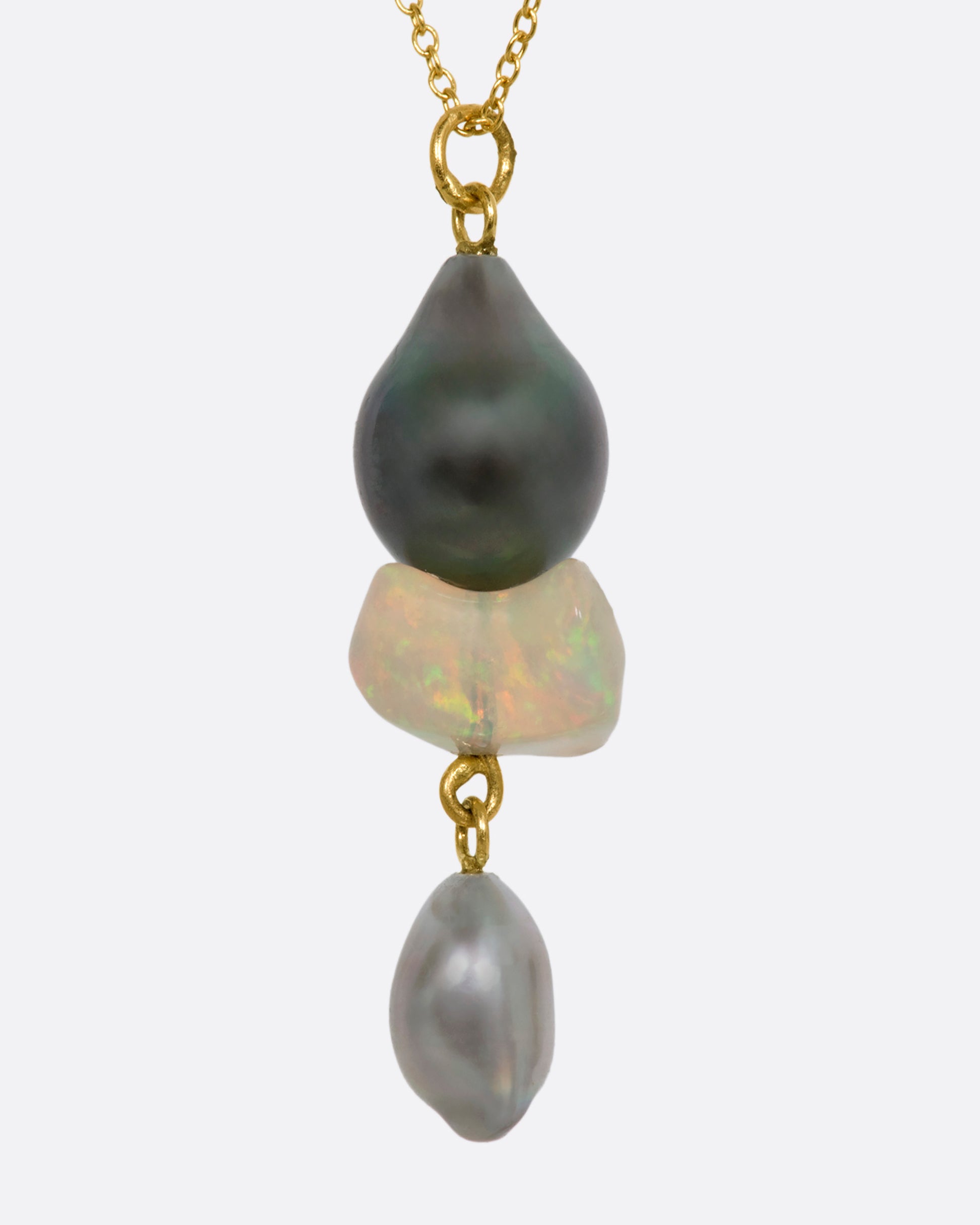 A yellow gold necklace with a triple drop pendant consisting of one opal and two pearls. View from the side.