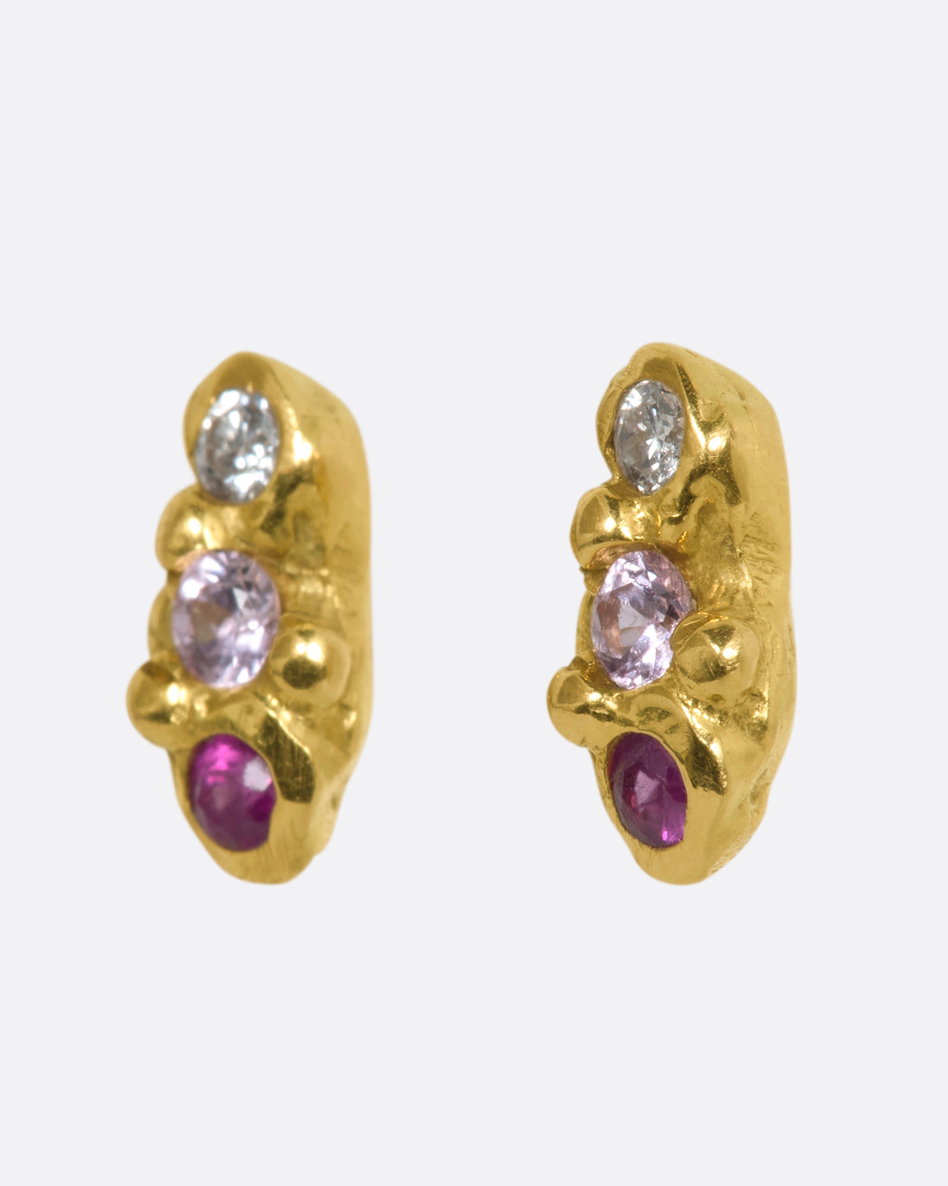 A pair of yellow gold bubble studs with diamonds, sapphires and rubies. Shown from the side.