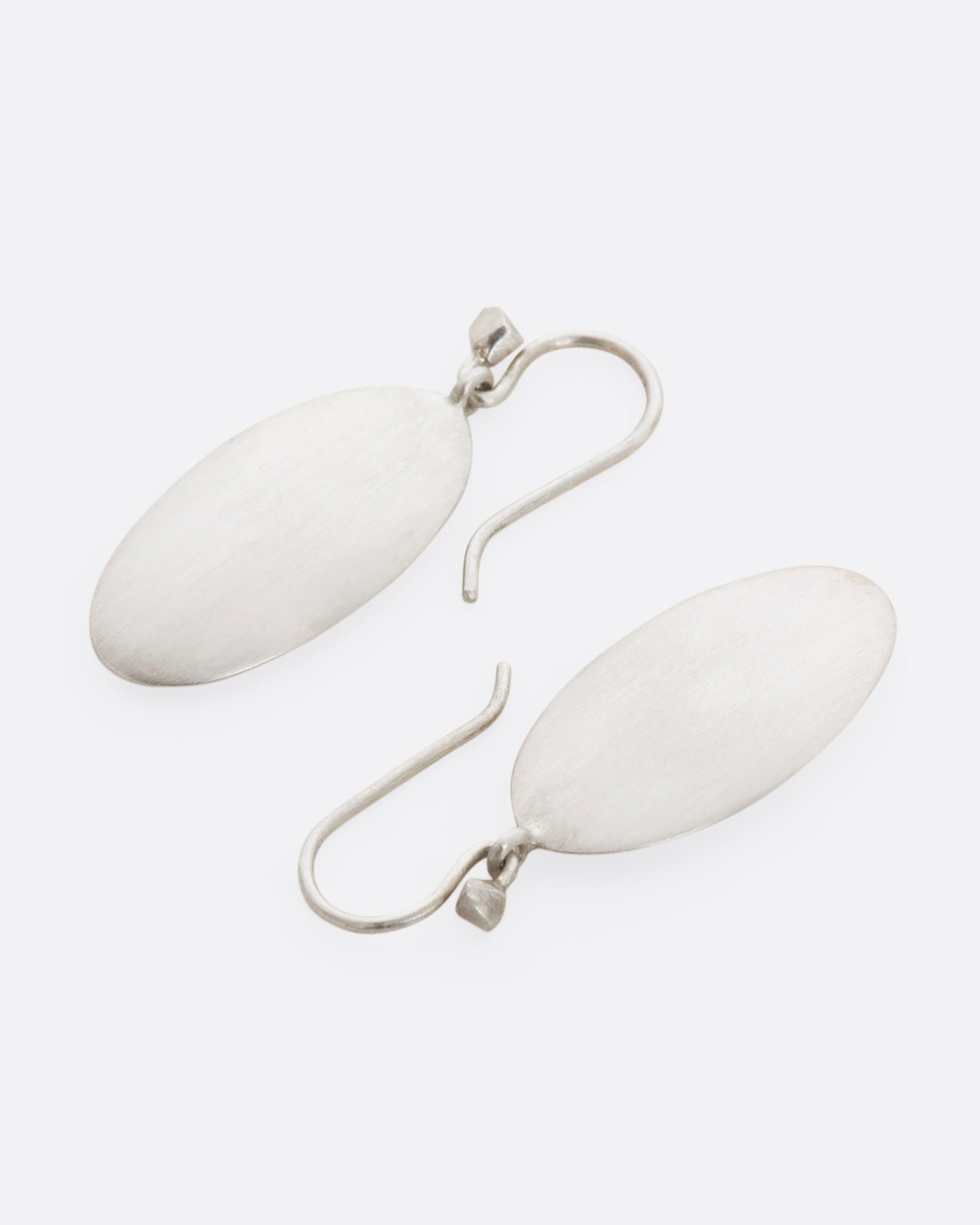 Sterling silver long flat oval dangle earrings. View laying flat.