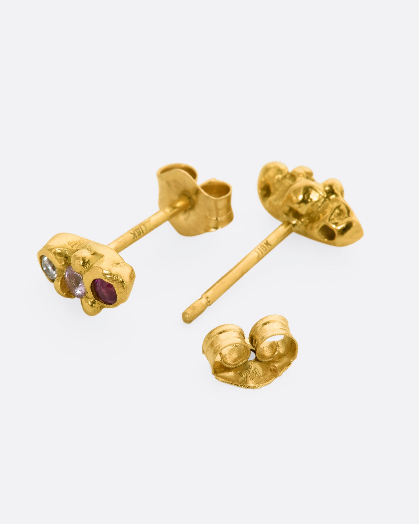 A pair of yellow gold bubble studs with diamonds, sapphires and rubies. Shown laying flat.