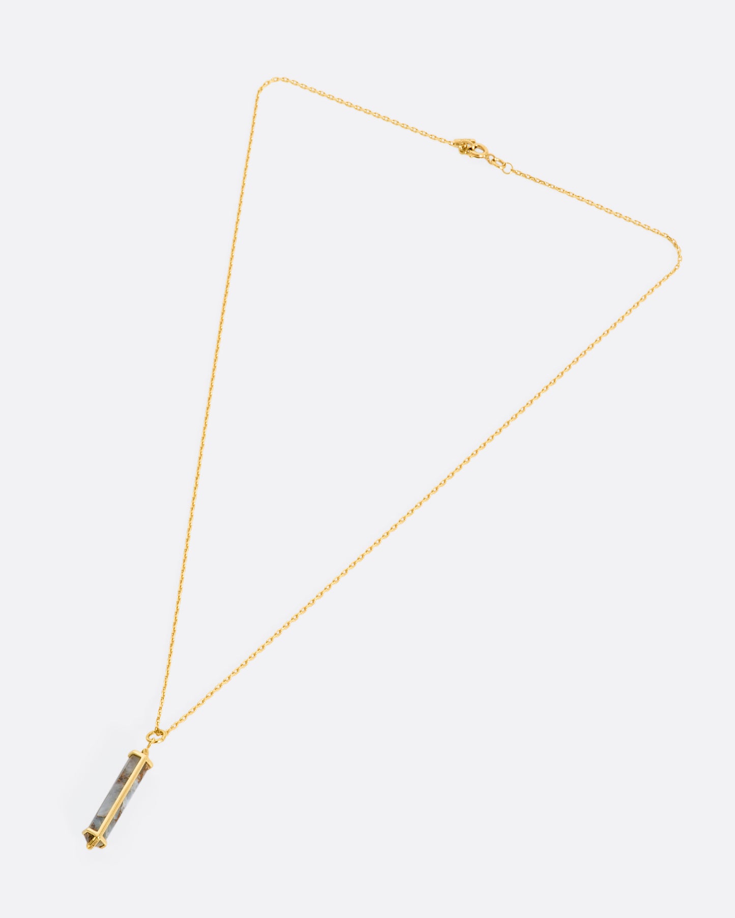 A yellow gold necklace with a geometric pink opal pendant. View laying flat.