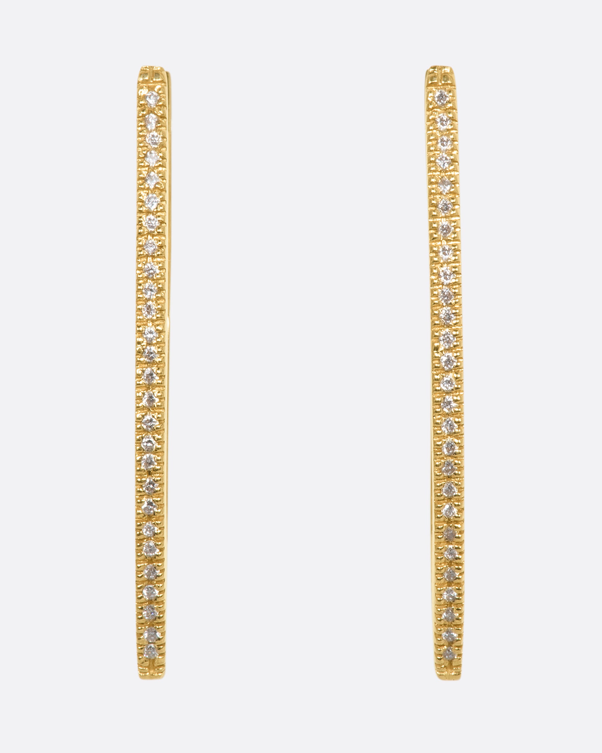 A pair of curved rectangle hoop earrings with pave diamonds. View from the front.