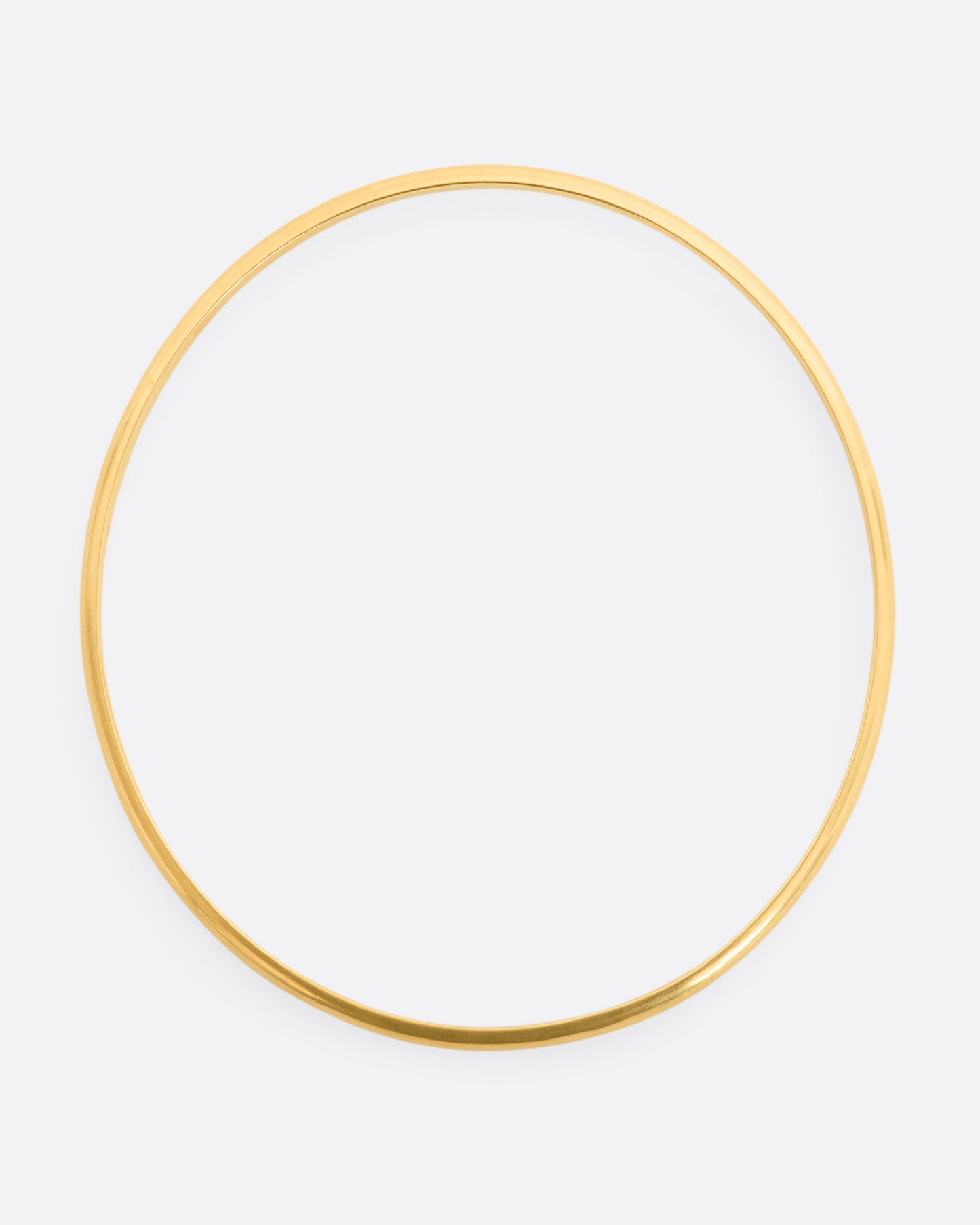 A yellow gold rounded bangle bracelet. Shown from above.