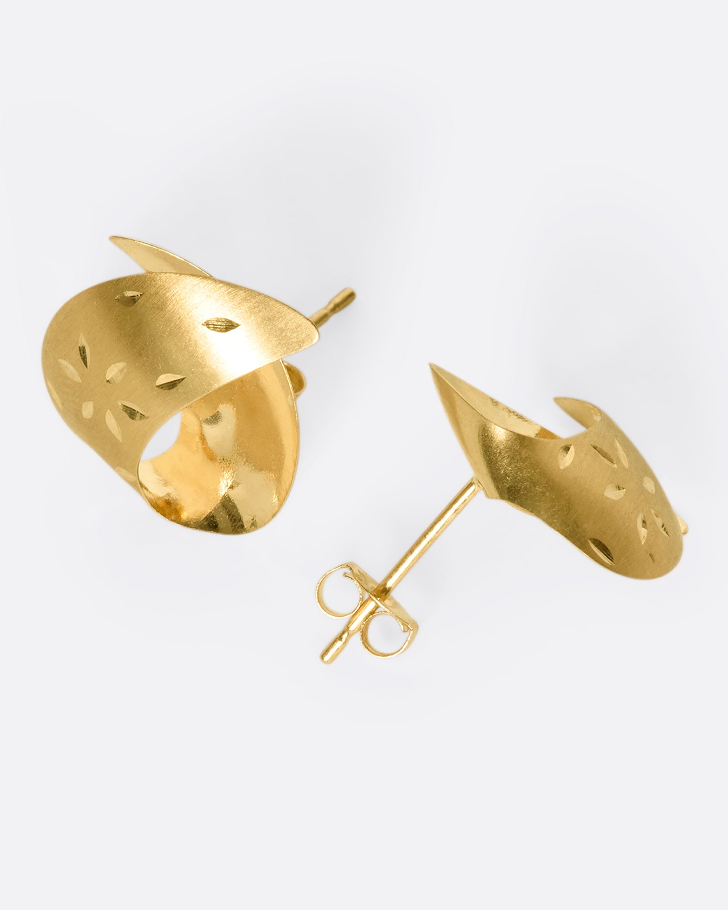 These vintage lightweight, folded studs are made of both matte and polished 14K gold. They're engraved with floral details that pick up light as you move.