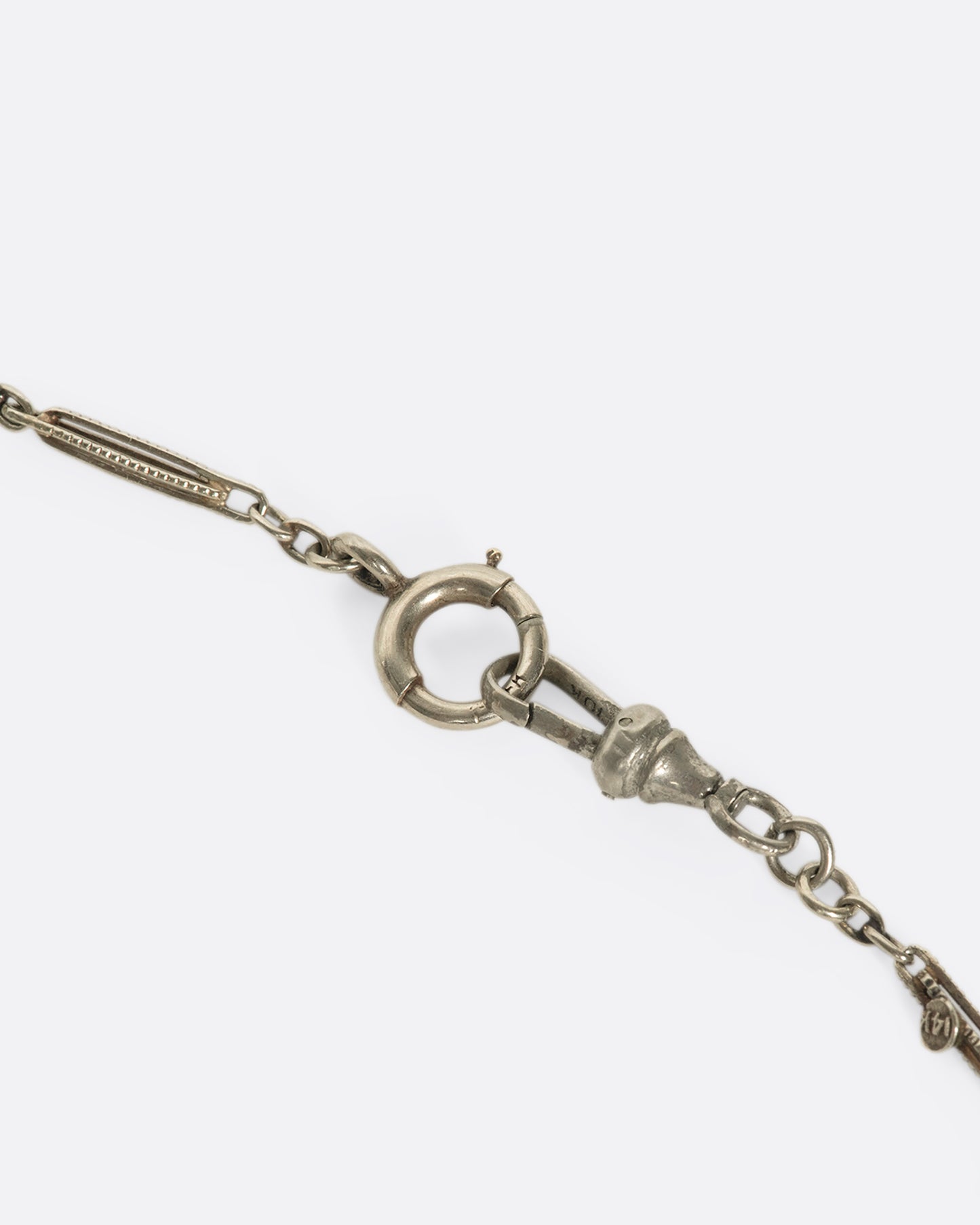 A close up of a white gold chain necklace clasp.