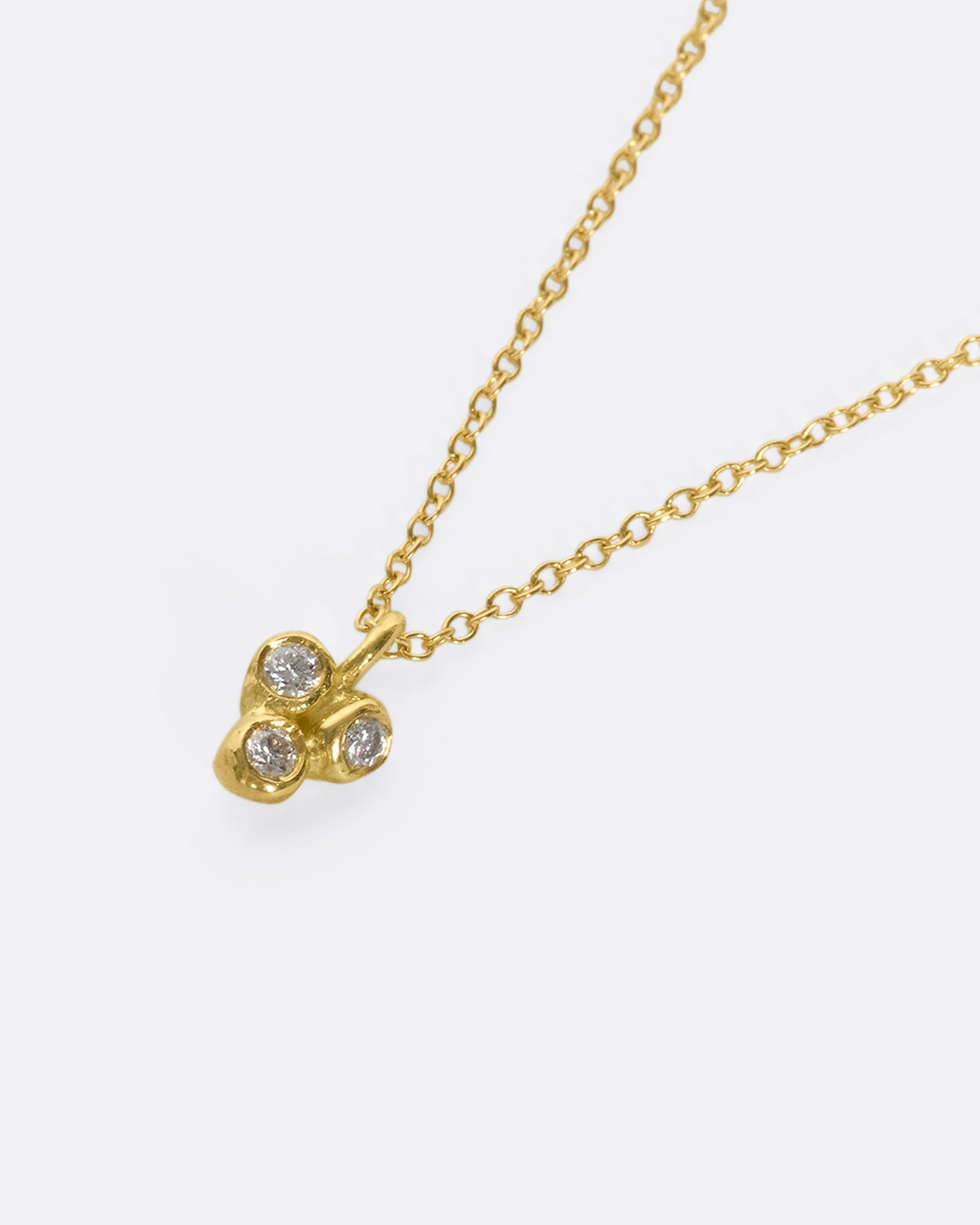 A dainty 18k gold and diamond pendant swinging on a fine gold chain