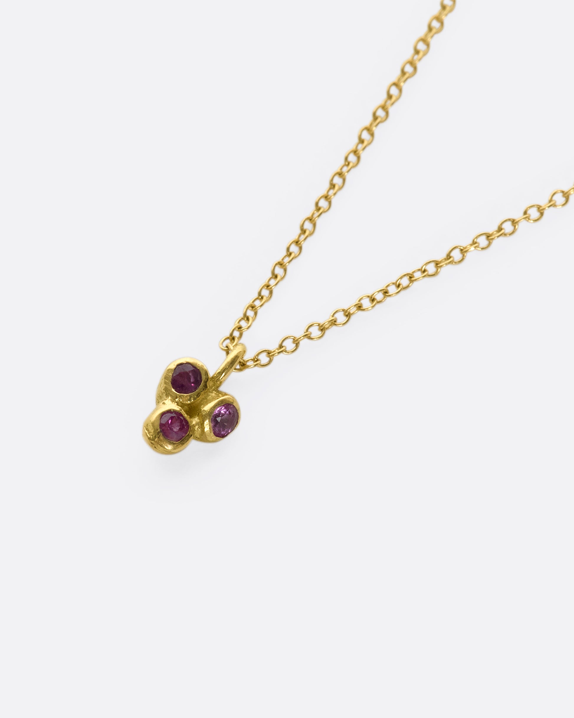 A sweet 18k gold and ruby pendant swinging on a fine gold chain