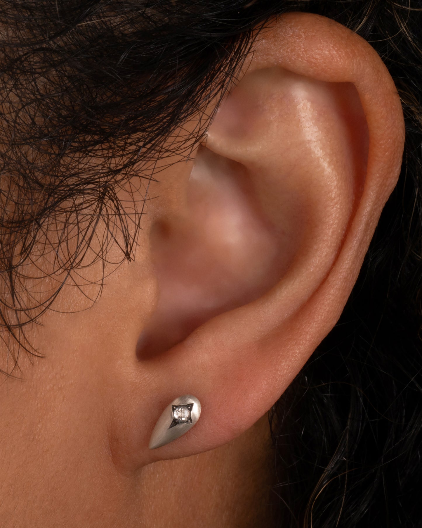 Silver teardrop shaped earrings with rose cut diamonds. Shown worn in an ear.