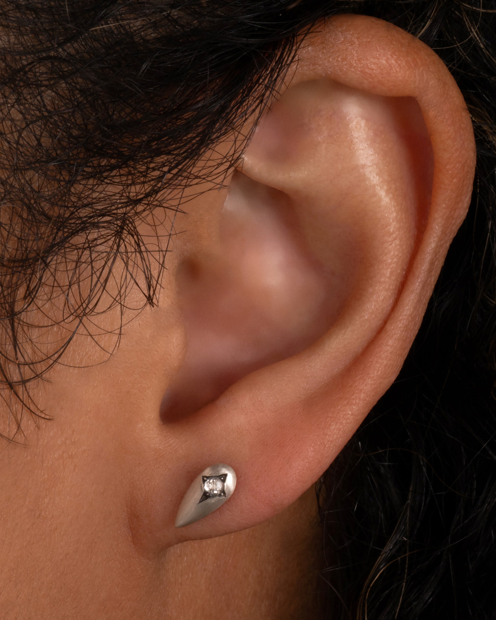 Silver teardrop shaped earrings with rose cut diamonds. Shown worn in an ear.