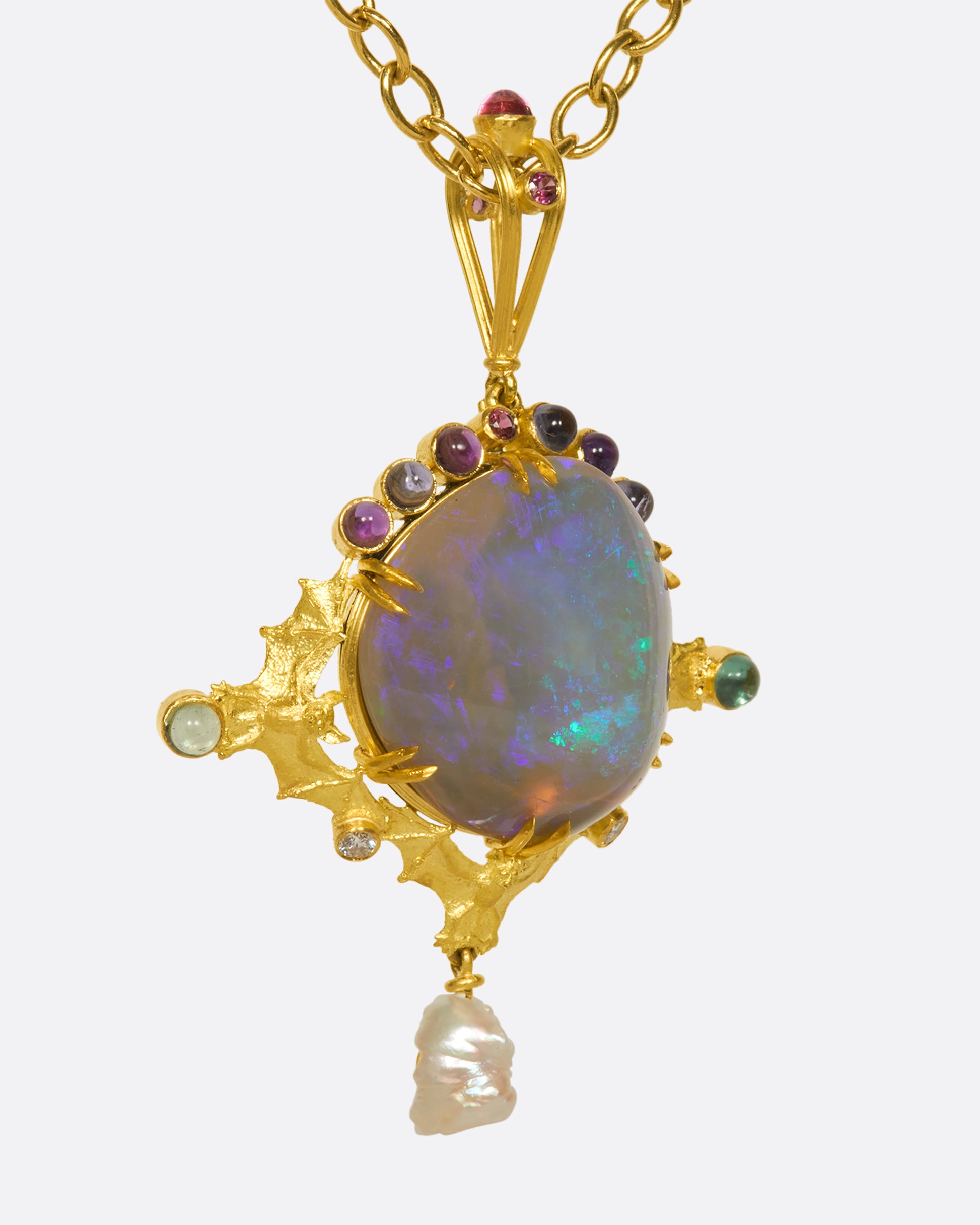 This incredible black opal pendant is held in place by three 18k gold bats and adorned with iolite, tourmaline, amethyst, natural pearl, and diamonds.