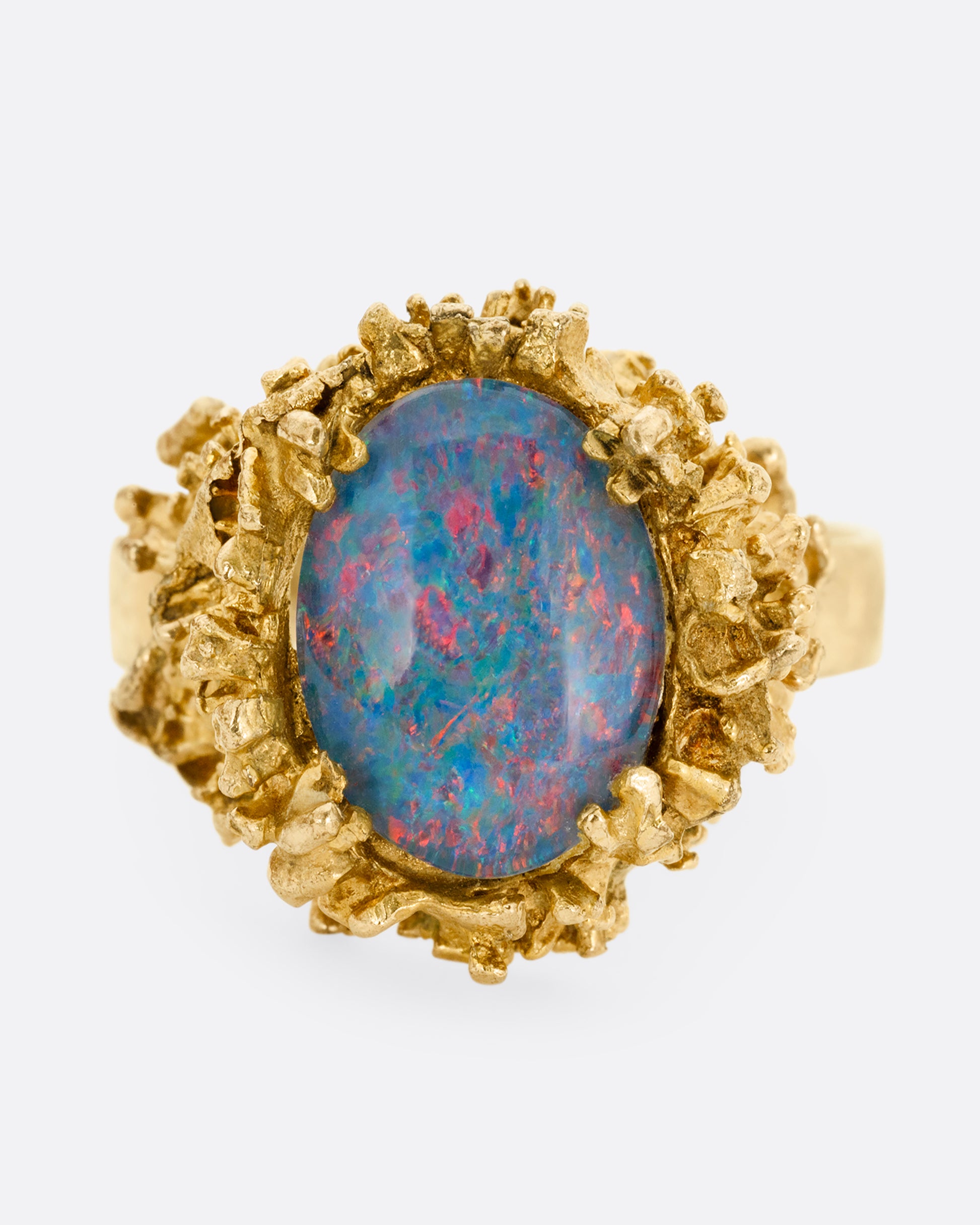 A yellow gold Brutalist era statement ring with an opal doublet in a molten gold nest. Shown from the front.