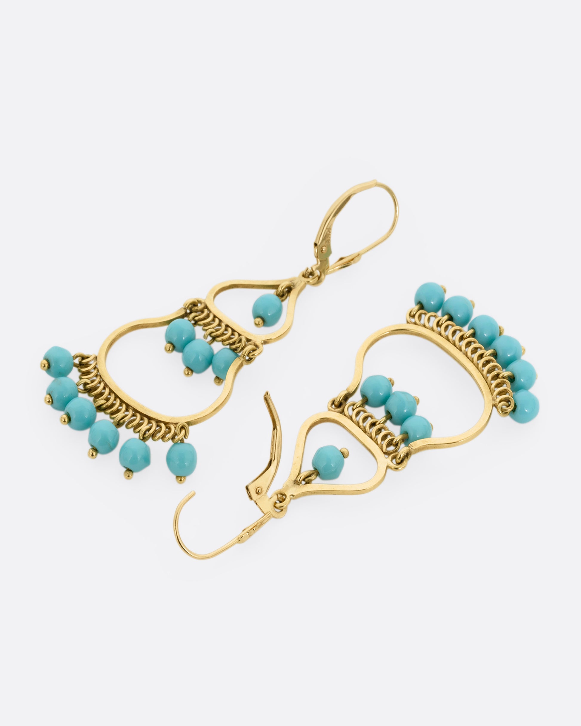 A pair of yellow gold  drop chandelier earrings with turquoise beads, shown lying flat from the back. One earring is shown open.