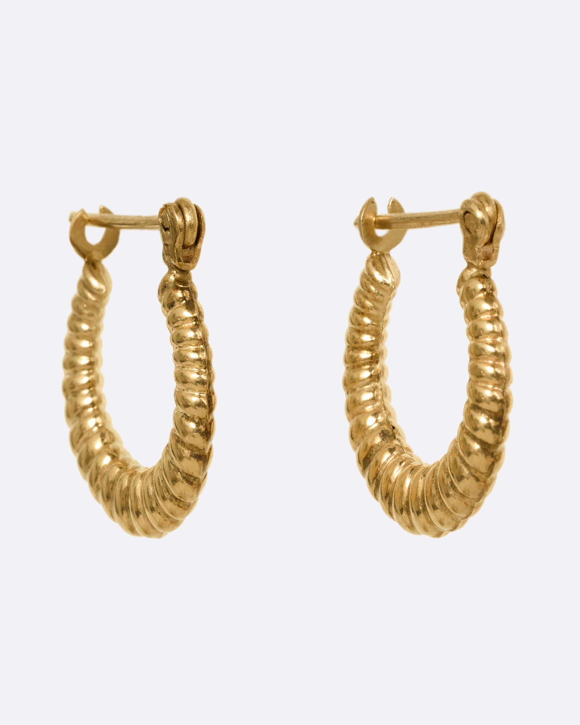 A pair of yellow gold ribbed hoop earrings shown from the side. 
