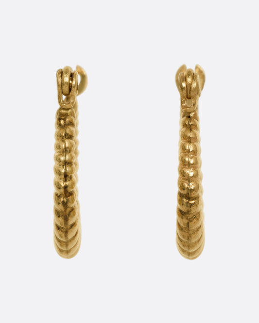 A pair of yellow gold ribbed hoop earrings shown from the front. 