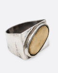 A silver signet ring with an oval shaped bone set diagonally across its face, shown from the side.