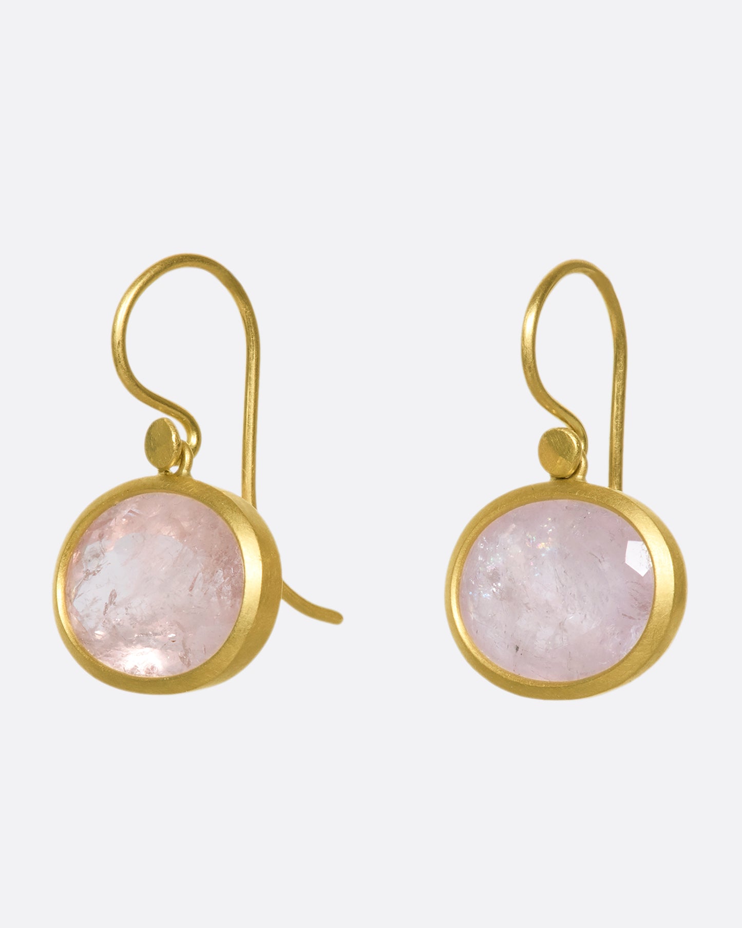 A side view of a pair of oval morganite drop earrings with yellow gold bezels and hooks.